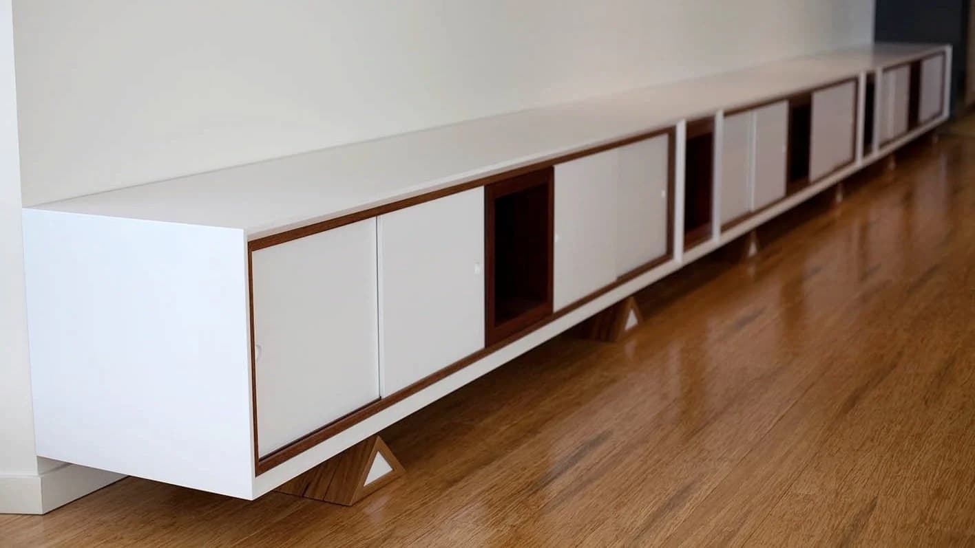 Grand meuble bas avec portes blanches et cadres en bois sur parquet — Mark Jackson Studios