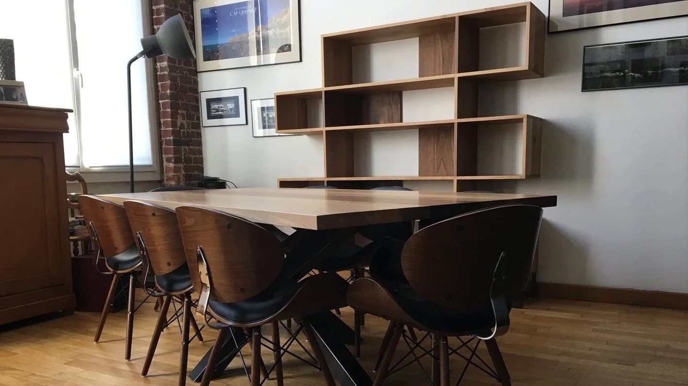 Salle à manger avec table en bois, chaises modernes et étagères murales
