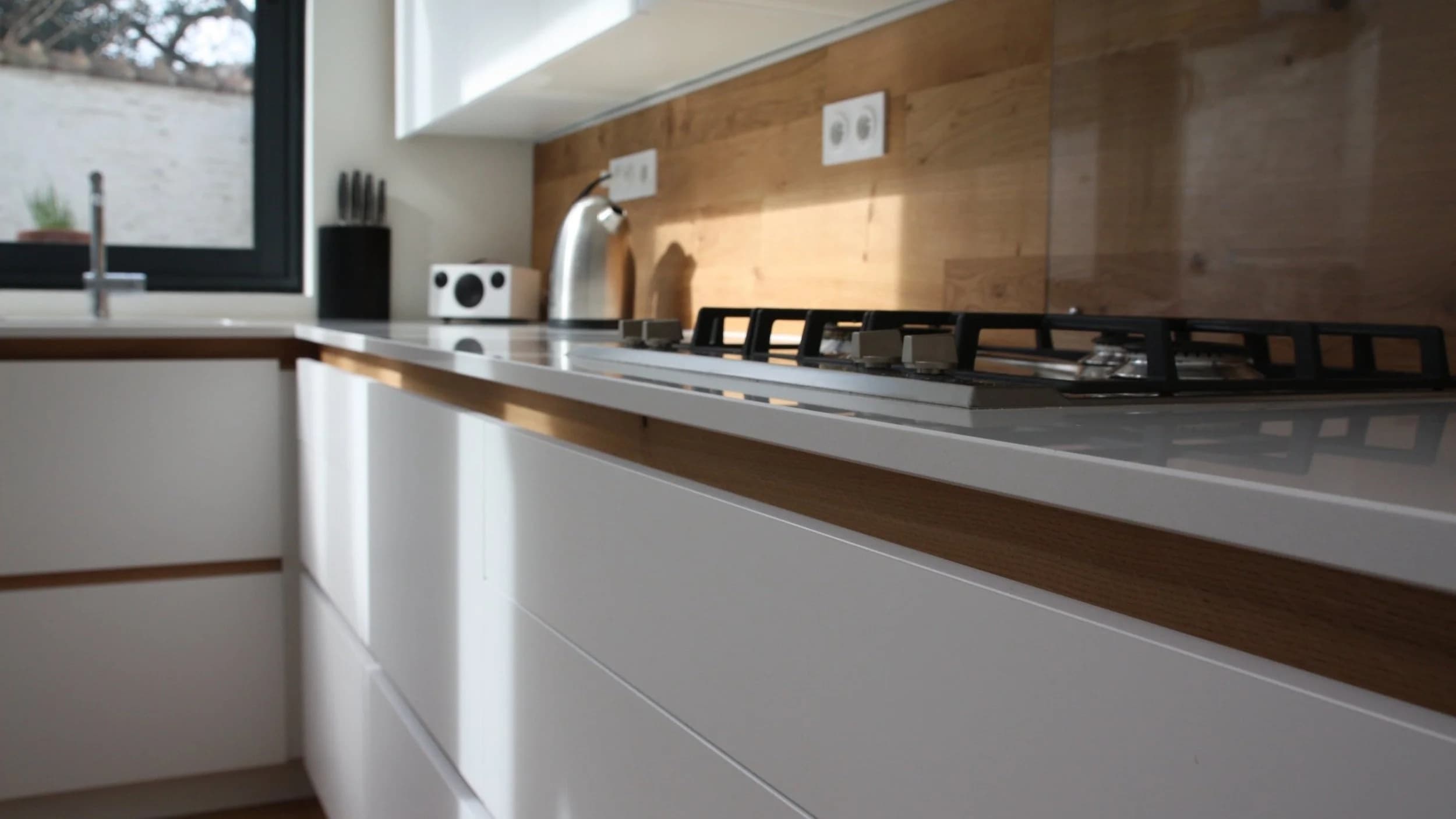 Cuisine moderne avec plaques de cuisson, comptoir blanc et mur en bois
