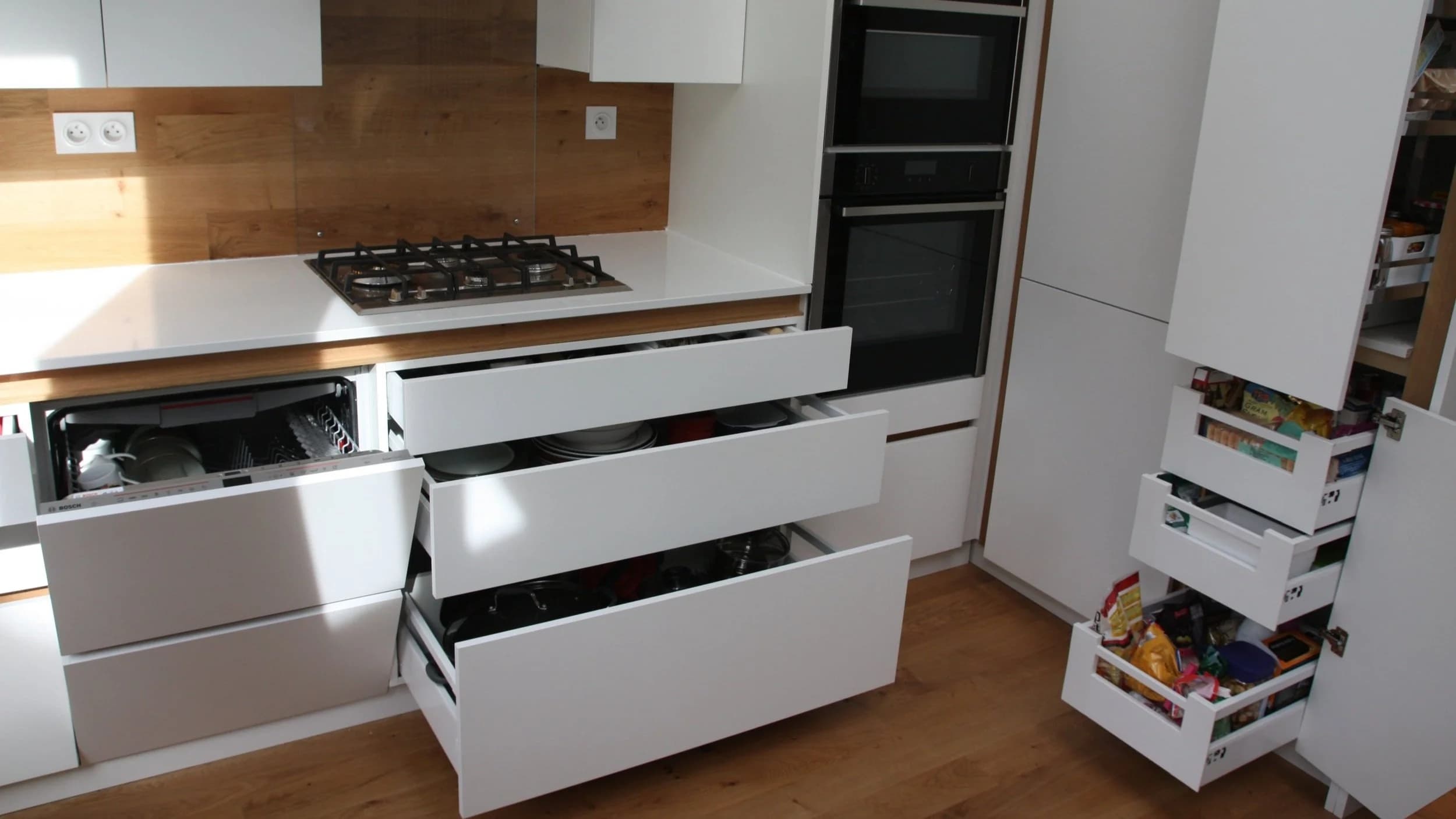 Cuisine moderne avec armoires blanches ouvertes montrant tiroirs et lave-vaisselle