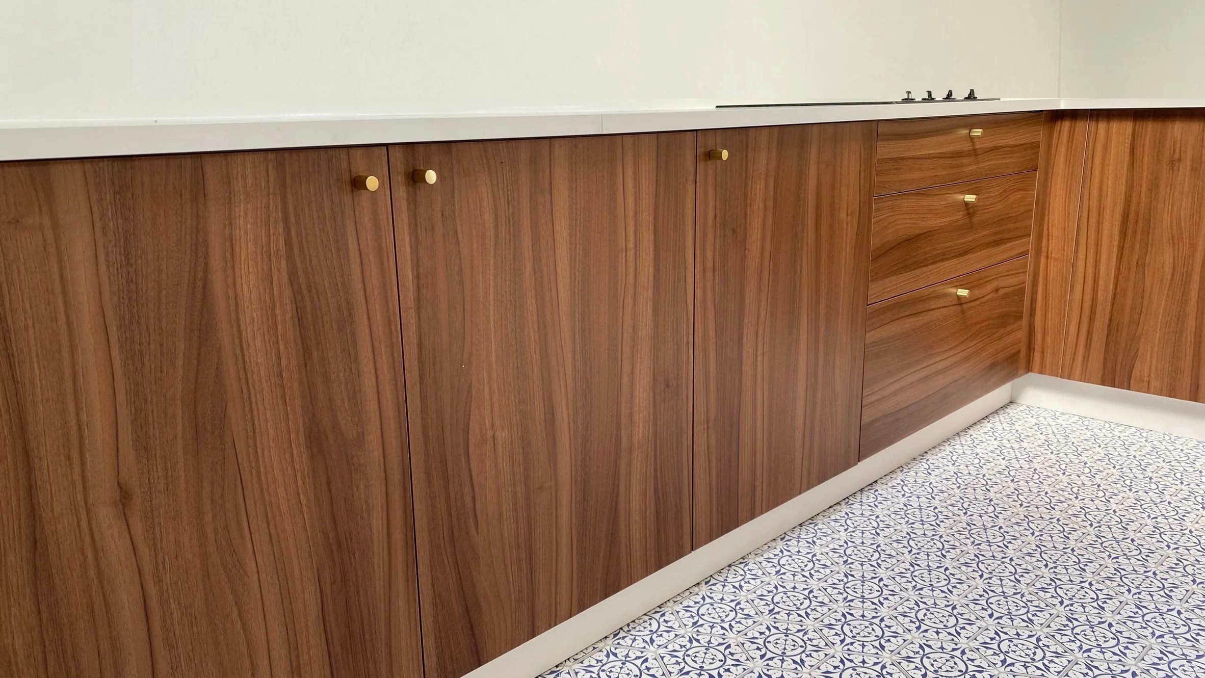 Cuisine moderne avec placards en bois, poignées dorées et sol en carreaux bleus et blancs