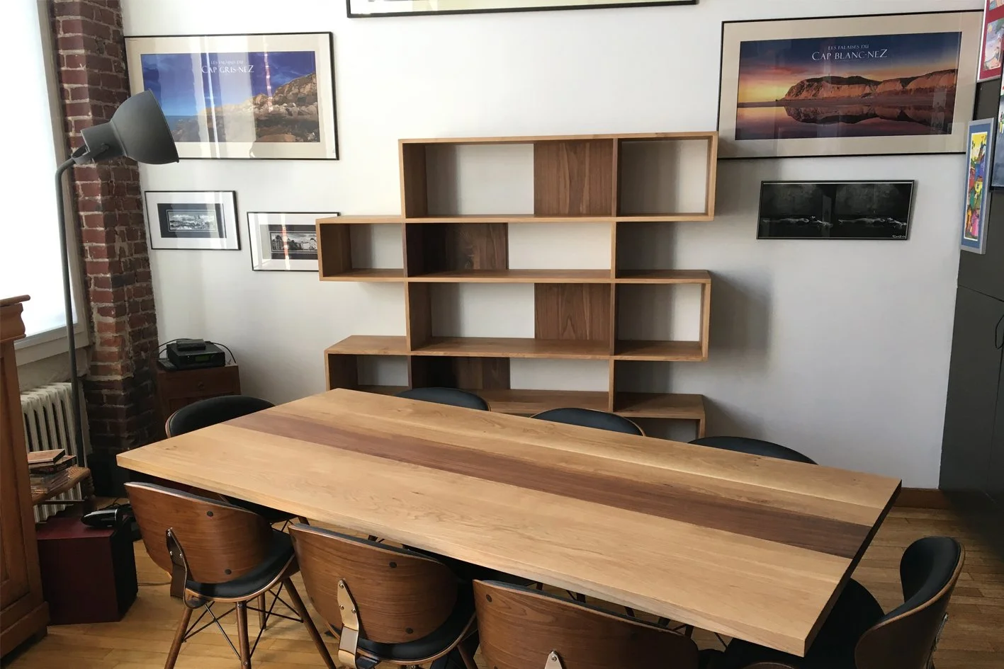 Salle de réunion avec grande table en bois, chaises, étagère murale